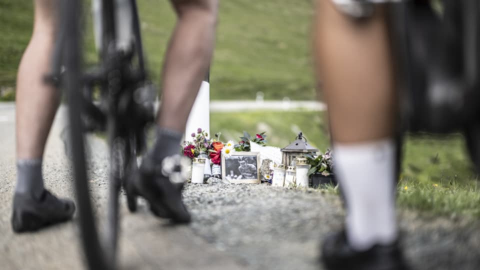 Radfahrer an der Gedenkstätte des verstorbenen Schweizer Rennfahrers Gino Mäder.