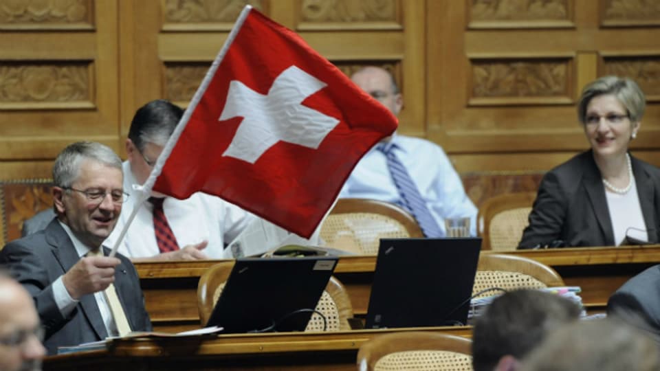 Walter Mueller (FDP/SG), schwenkt eine Schweizerfahne während den Beratungen über das Amtshilfegesuch der USA betreffend der UBS 2010 im Nationalrat.