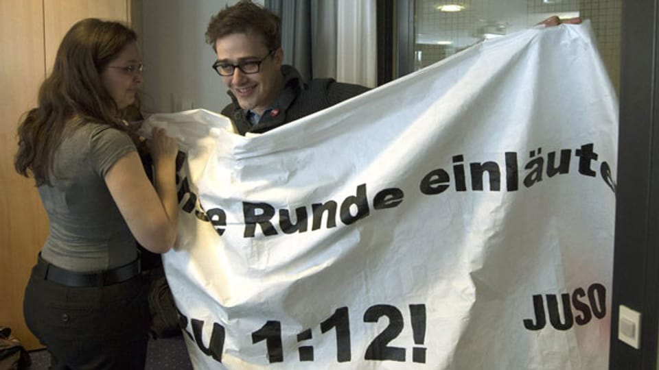 JUSO Präsident David Roth versucht, mit einem Plakat zur 1:12 Initiative «Für gerechte Löhne» das Abstimmungslokal von Economiesuisse zu stören am, 3. März 2013, in Bern.