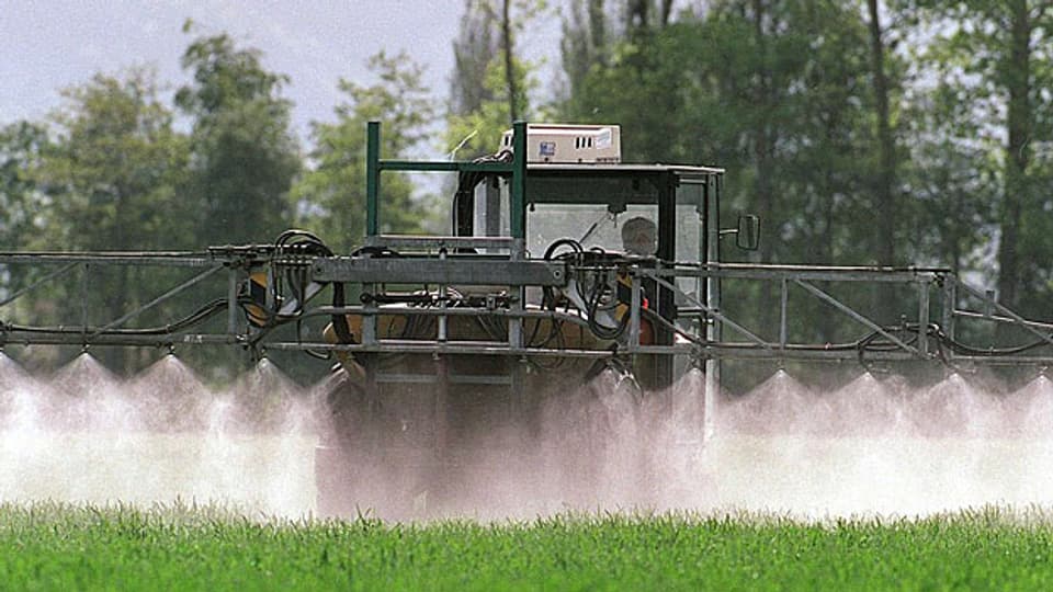 Ein Landwirt verprüht Pestizide auf einem Feld; diese landen unweigerlich in Bächen oder Seen.