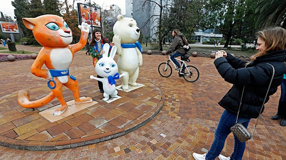 Eine Touristine fotografiert die drei Maskottchen der Olympischen Spiele.