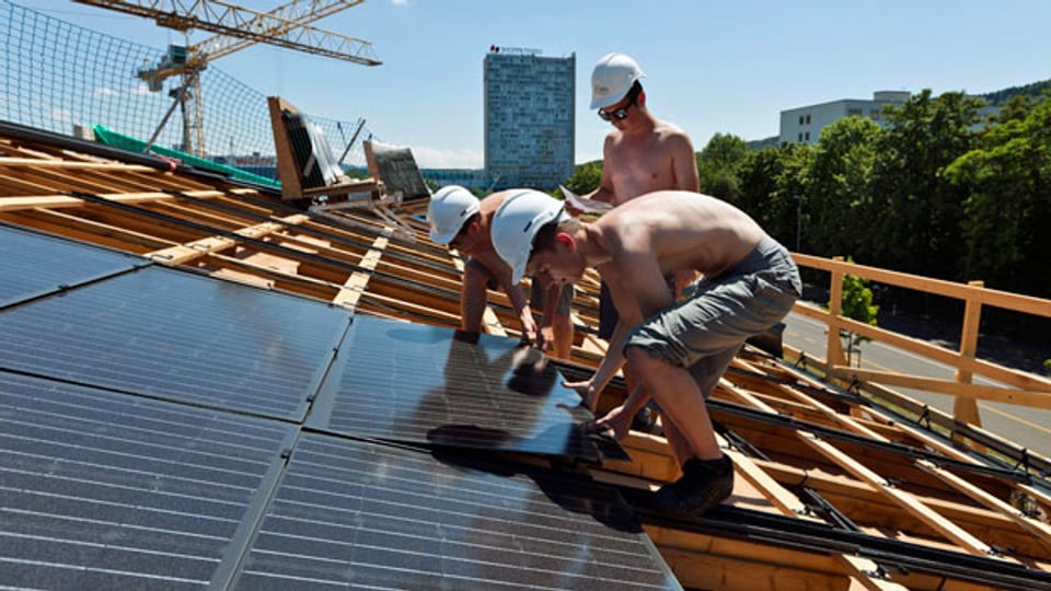 Bauarbeiter montieren eine Solaranlage. Symbolbild.