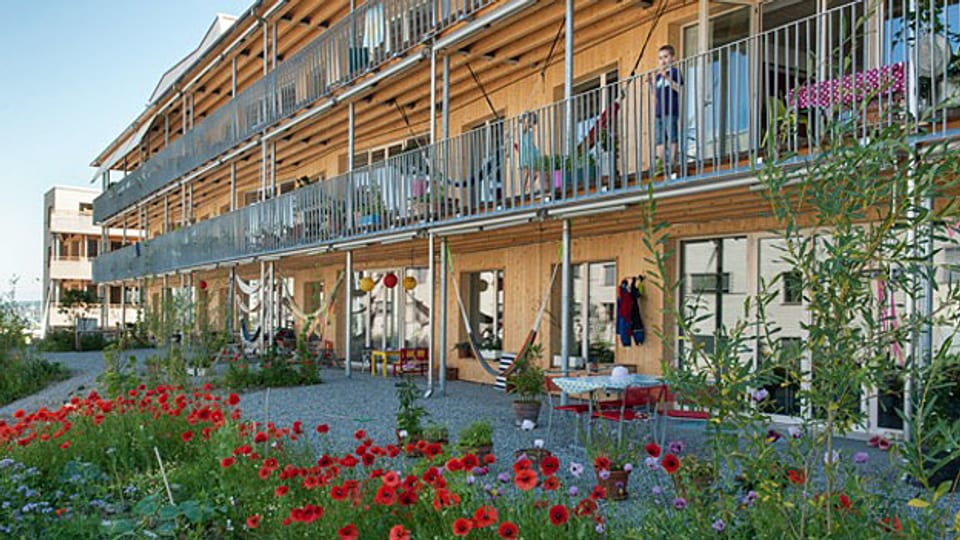 Die Siedlung Oberfeld in Ostermundigen: Vierstöckige Häuser, Holzverkleidungen, viele Balkone - rund 100 Wohnungen.  Es gibt Gemeinschaftsräume, einen grossen gemeinschaftlichen Garten und bald soll noch eine Aussen-Sauna dazu kommen.