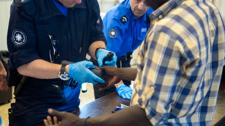 Ein Asylbewerber gibt seinen Fingerabdruck beim Personal des Grenzwachcorps am Zoll des Bahnhofs Chiasso.