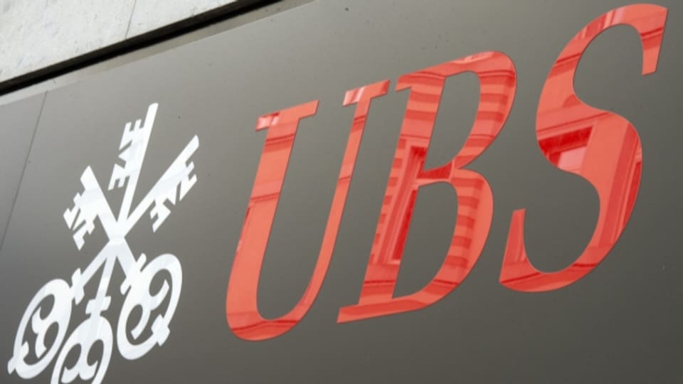 Zu sehen ist das rote Logo der Grossbank UBS auf einer grauen Hausfassade.