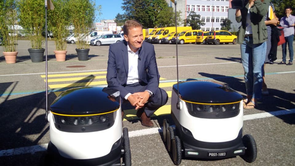 Dieter Bambauer, Leiter PostLogistics, demonstriert in Bern eine Paket-Lieferung mit zwei Robotern.