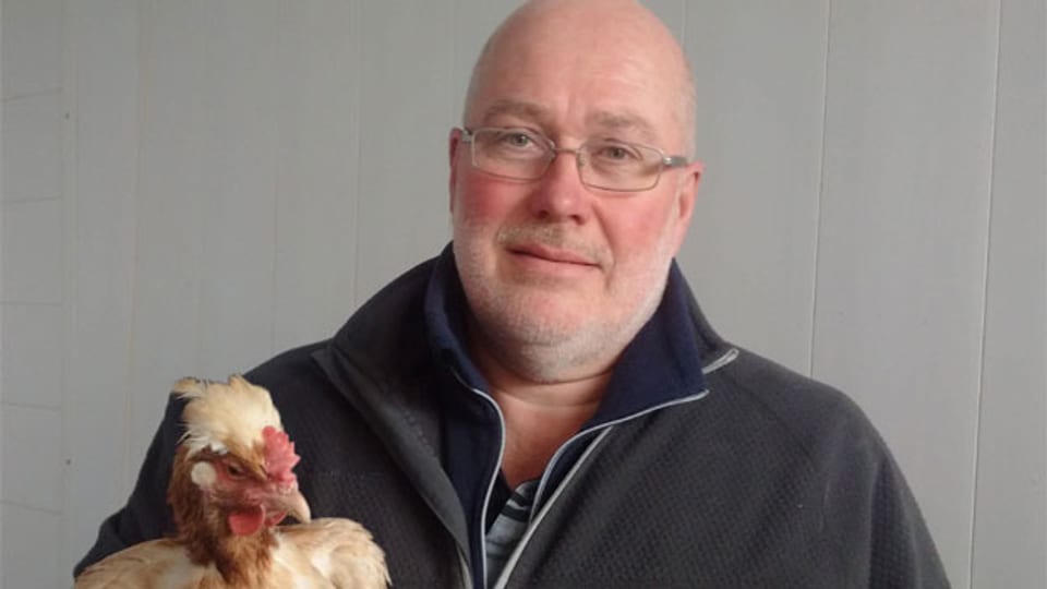 Lukas Meier vom Hof Maiengrün in Hägglingen mit einem steierischen Sulmtaler Huhn auf dem Arm.