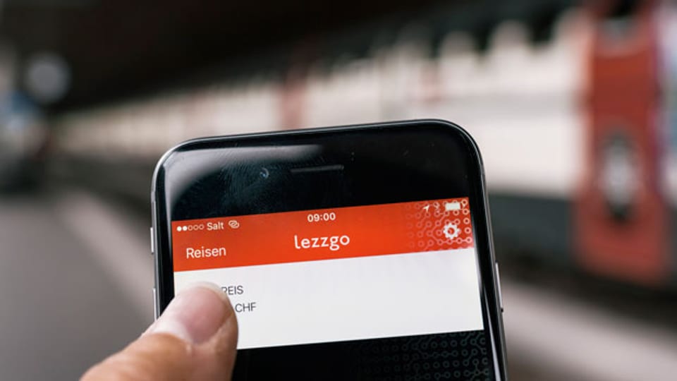 Ein Smartphone mit der Mobile Ticketing App lezzgo, im Hintergrund ein Personenzug der SBB.