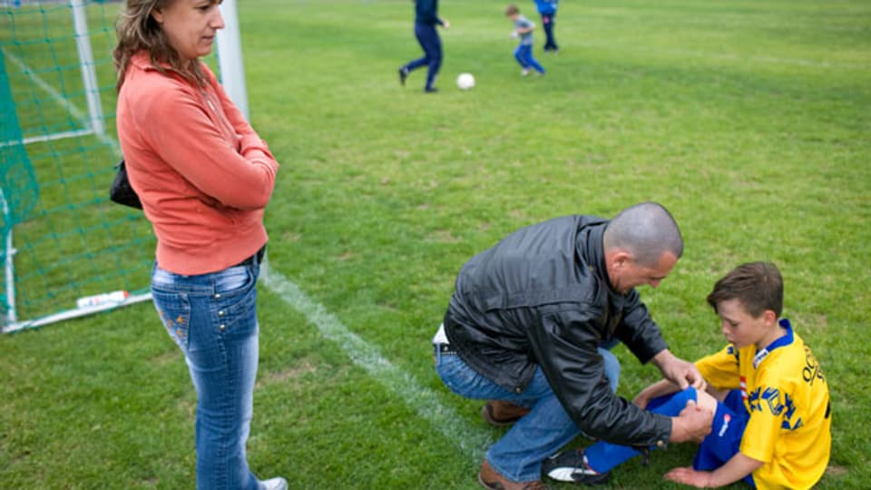 Ein Vater betreut seinen Sohn auf dem Fussballplatz.