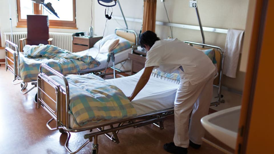 Eine Pflegefachfrau macht ein Krankenbett in einem Regionalspital.