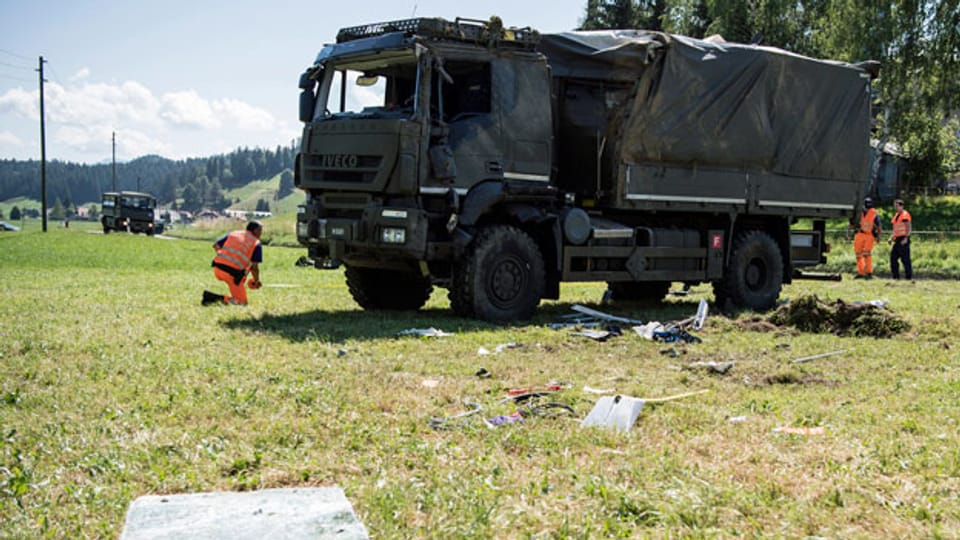 Zwei Polizisten untersuchen einen verunfallten Lastwagen der Armee, in Linden bei Oberdiessbach.