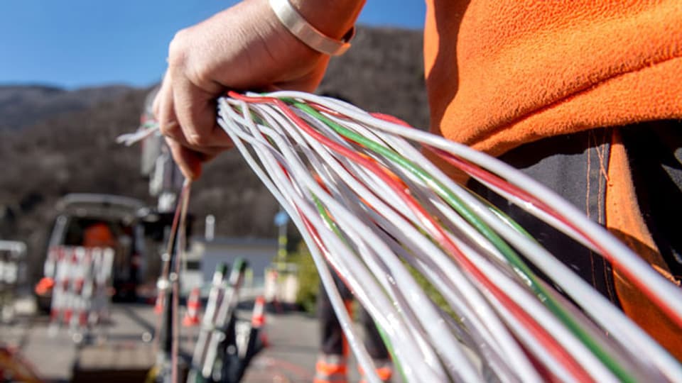 Ein Arbeiter montiert Glasfaserkabel der Swisscom für den Internetanschluss von Privathaushalten.
