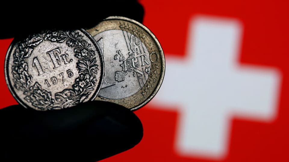 Symbolbild. Schweizer Franken und Euro vor einer Schweizer Fahne.