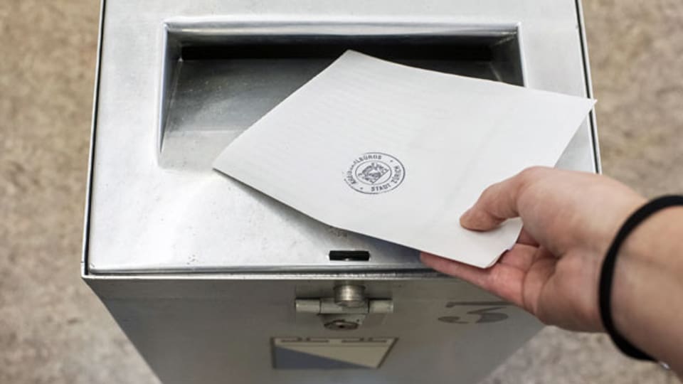 Eine Frau wirft ihre Abstimmungsunterlagen zur Ständerats- und Nationalratswahl in die Urne.