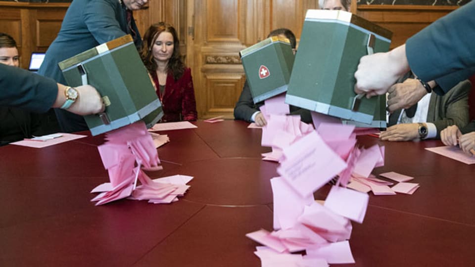 Weibel leeren bei den Stimmenzählern und -zählerinnen die Urnen mit den Wahlzetteln aus.