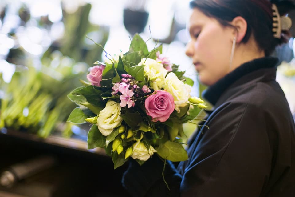 Eine Floristin der Blumenhalle am Pelikanplatz in Zürich bindet einen Strauss.