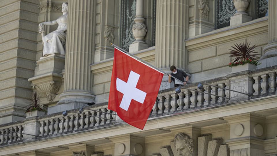 Eine Schweizerfahne wird beim Bundeshaus gehisst.