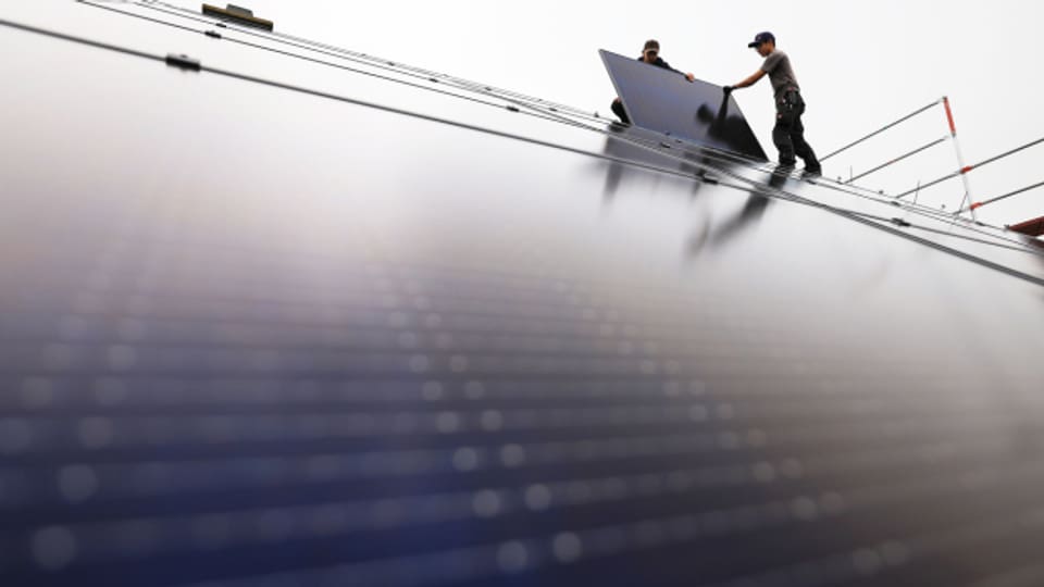 Solarinstallateure montieren Solarmodule auf dem Dach eines Wohnhauses.