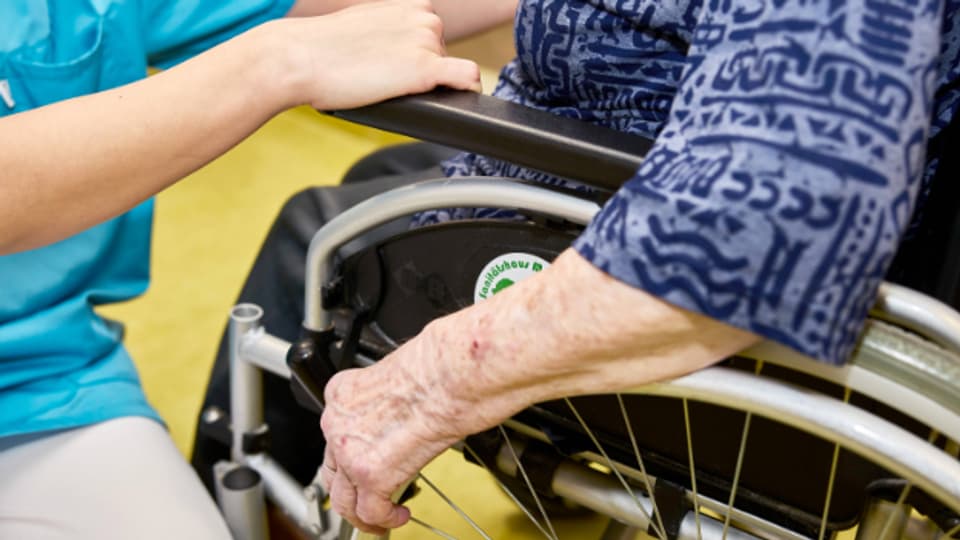 Symbolbild. Eine Pflegekraft betreut eine ältere Frau im Rollstuhl.