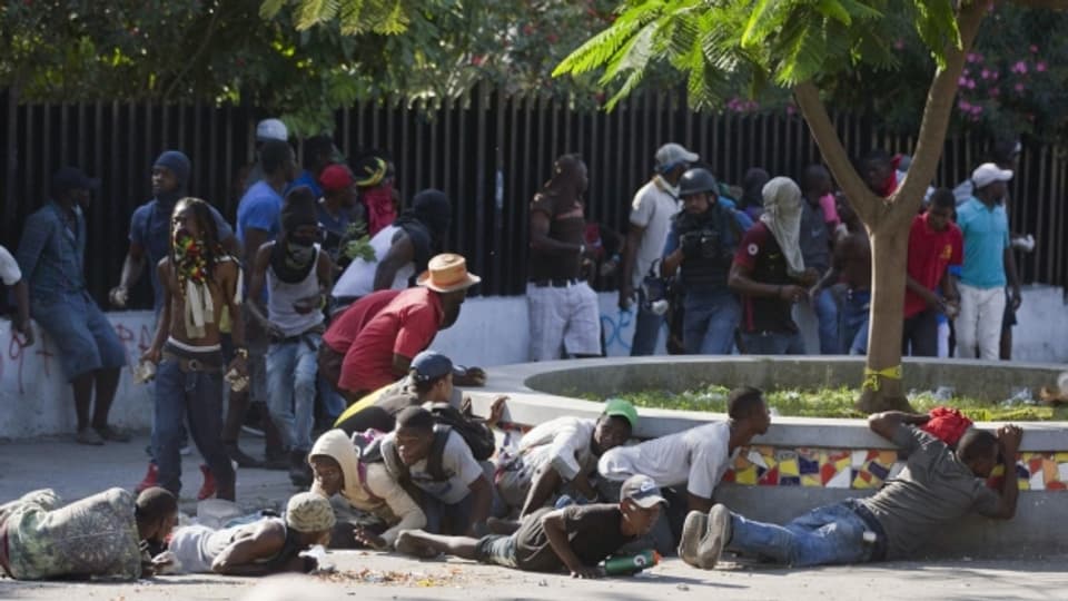 Demonstranten gehen in Port-au-Prince vor den Schüssen der Polizei in Deckung.