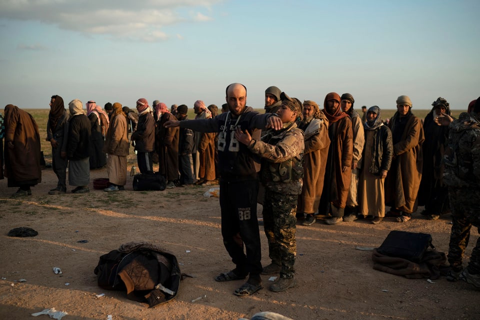 Ein Kämpfer der SDF durchsucht einen Verdächtigen in der Nähe von Baghuz.