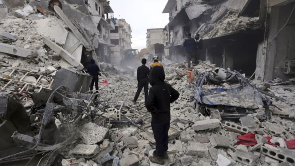 Syrische Retter verwenden einen Bulldozer, um Trümmer eines zerstörten Gebäudes zu entfernen.