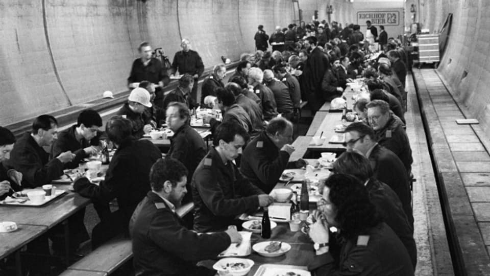 Zahlreiche Zivilschützer sitzen während der Übung «Ameise» im Luzerner Sonnenbergtunnel zum Essen zusammen (19. November 1987).