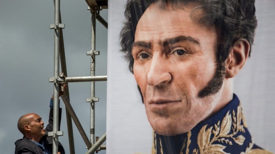 Ein Mann schaut auf ein Portrait von Simón Bolívar