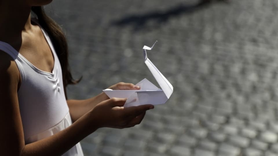 Ein Kind hält einen Origami-Kranich zum Jahrestag des Atomabwurfs über Hiroshima.