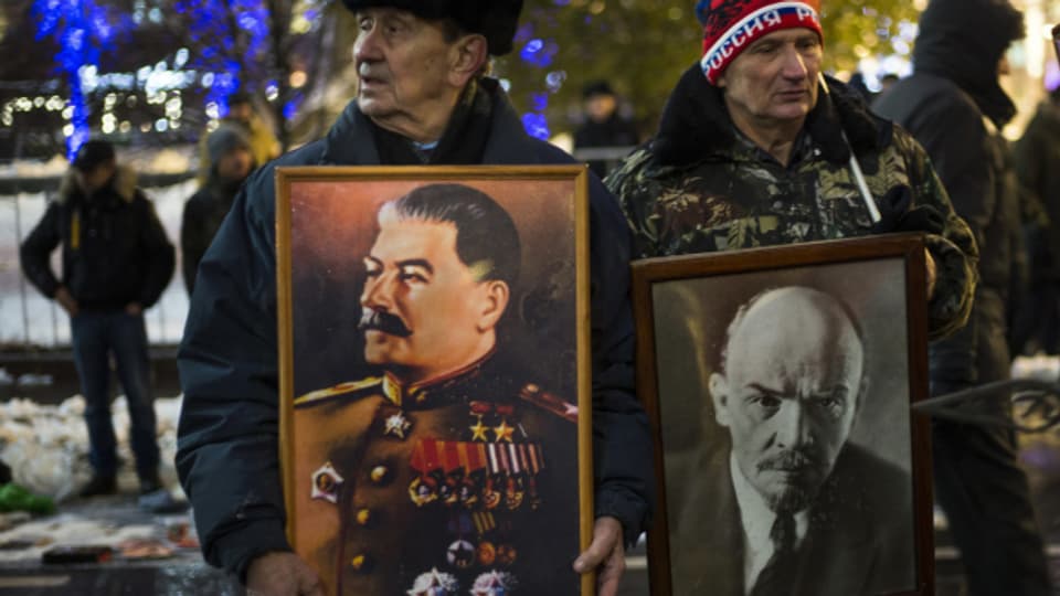 Zwei Männer feiern die Russische Revolution 1917 mit Bildern von Stalin und Lenin