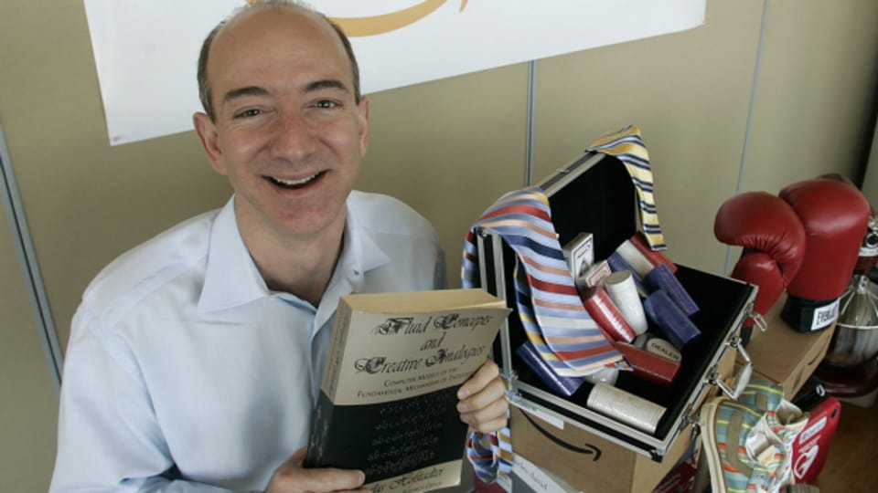 Amazon-Gründer Jeff Bezos zeigt das erste verkaufte Buch.