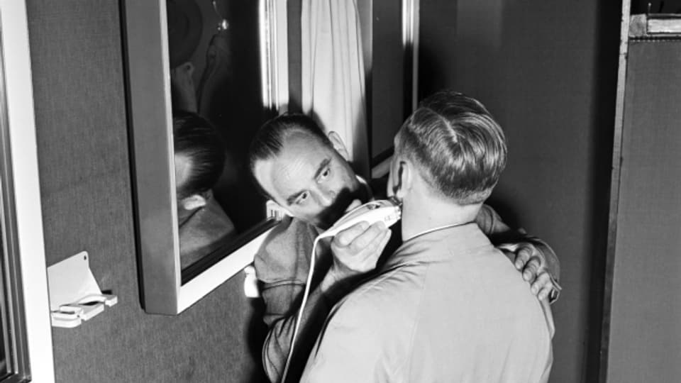 Ein Besucher wird an der 37. Mustermesse in Basel mit einem Elektrorasierer rasiert, aufgenommen im April 1953.