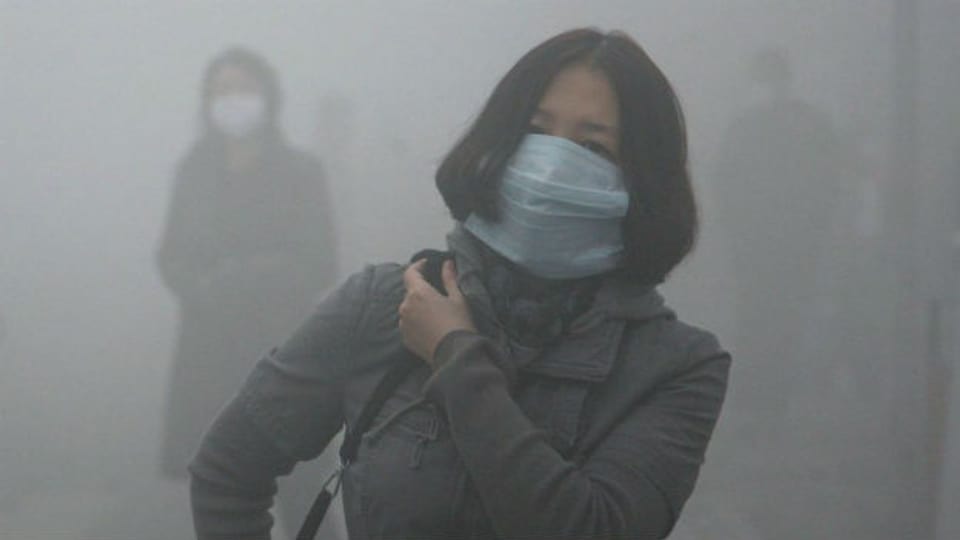 Frau mit Atemmaske im Smog von Harbin.