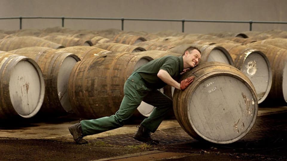 Ein Angestellter der Produktion transportiert Whisky-Fässer.