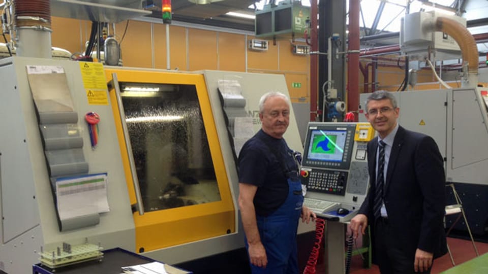 Der Firmenchef von Fraisa SA, Josef Maushart, (rechts) steht mit einem Mitarbeiter neben einer neuen Maschine.
