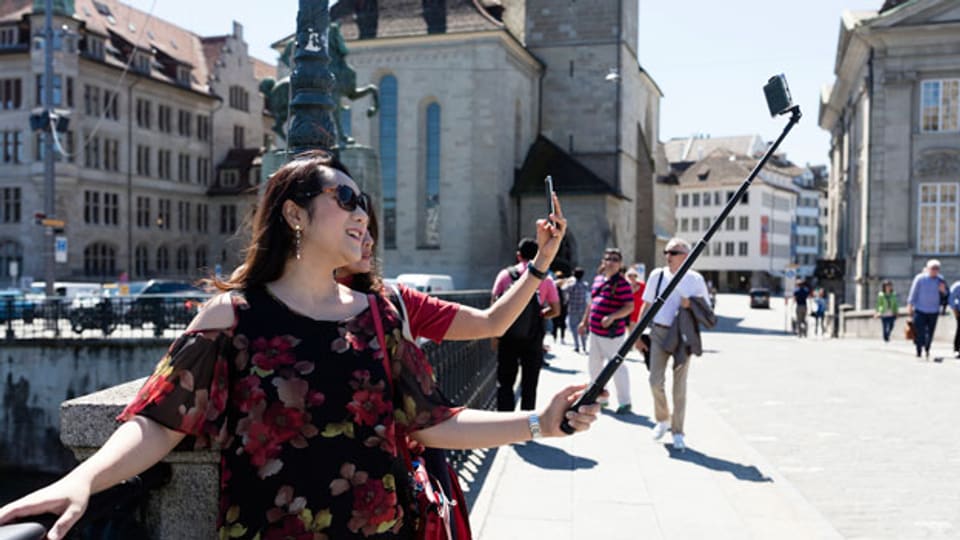 Asiatische Touristen machen auf der Münsterbrücke in Zürich Selfies.
