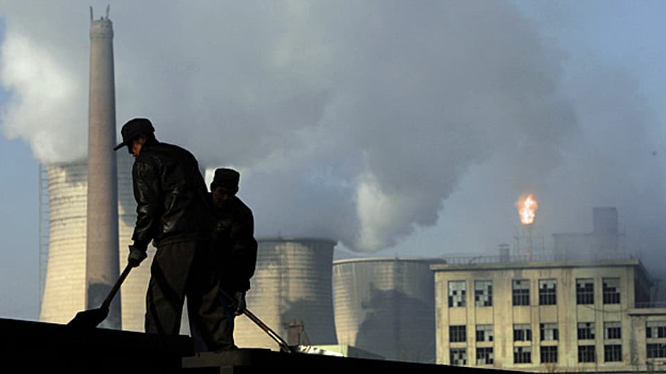 Arbeiter schaufeln Kohle vor einem chinesischen Kohlekraftwerk.