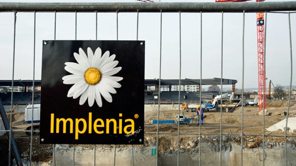 Das Logo der Bau-Unternehmung Implenia an einer Baustelle.