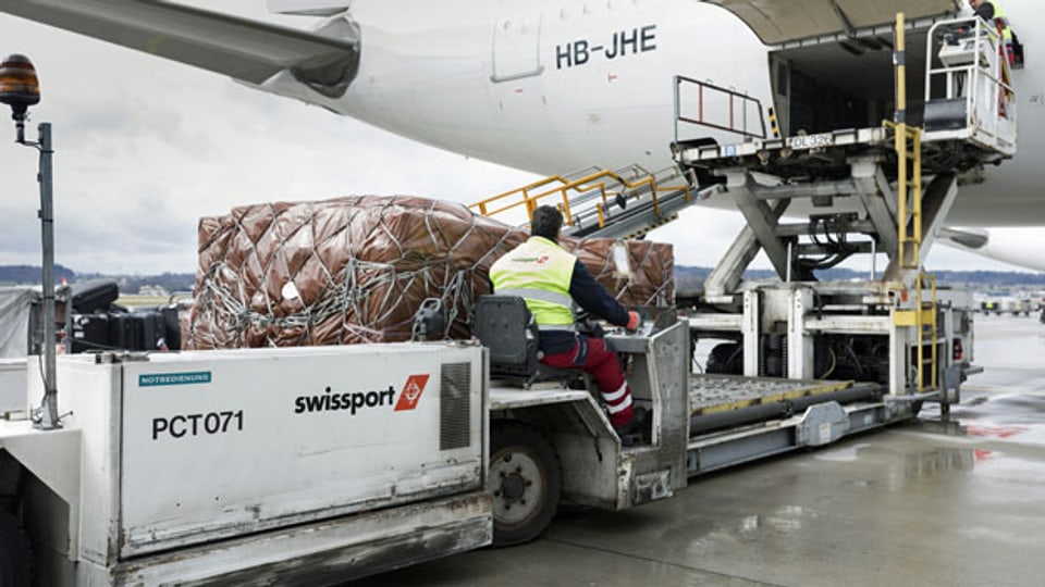 Ein Swissport-Mitarbeiter belädt den Frachtraum eines Flugzeugs am Flughafen Zürich.
