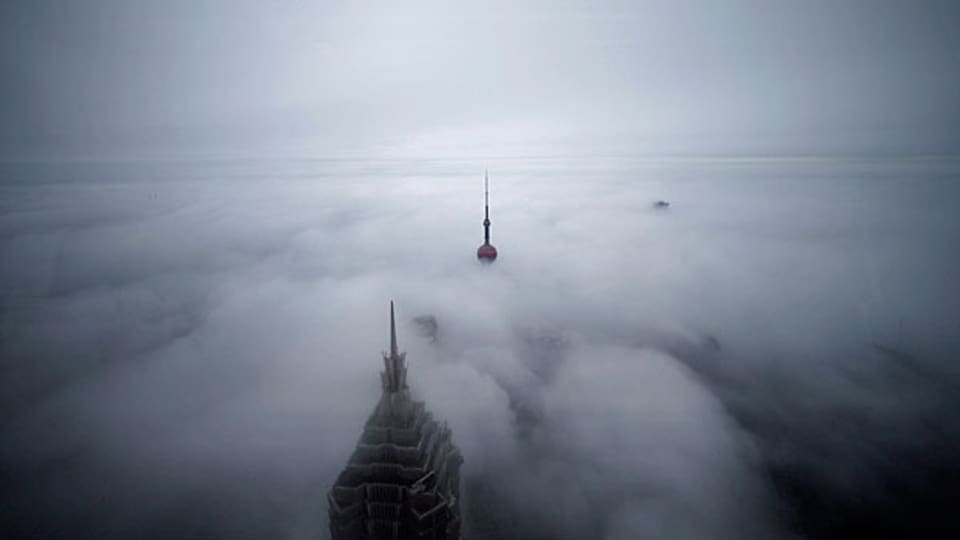 Seit einigen Jahren wird die Luft in manchen Teilen der Welt wieder schlechter, vor allem in China und Indien. Dies könnte die Klima-Erwärmung wieder bremsen. Bild: Wolkenkratzer ragen im Finanzdistrikt von Shanghai aus dem Smog.