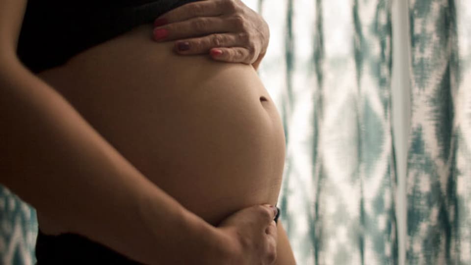 Eine schwangere Frau hält sich den Bauch. Symbolbild.