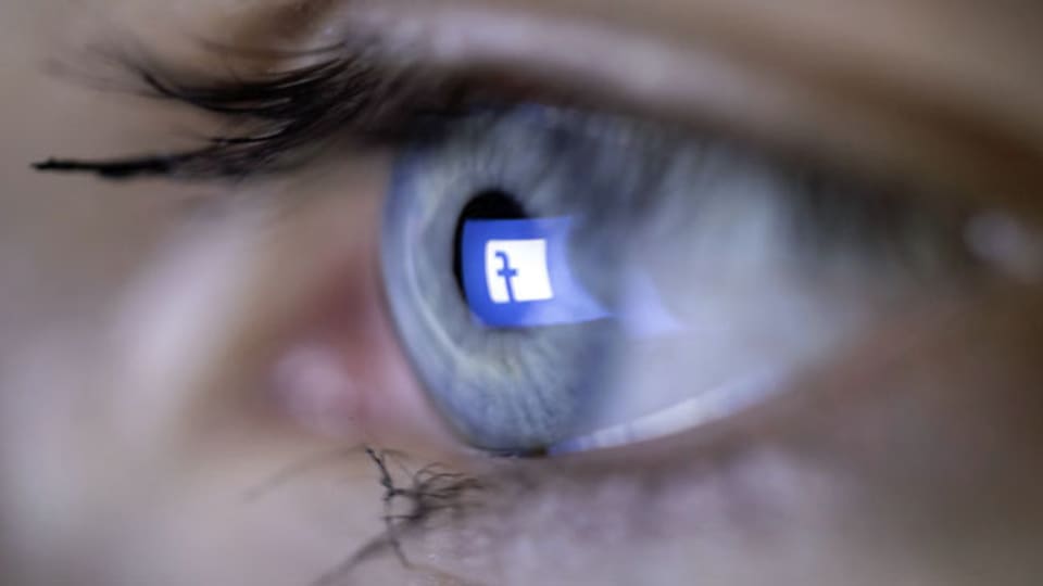 Das Logo von Facebook spiegelt sich einem Auge. Symbolbild.