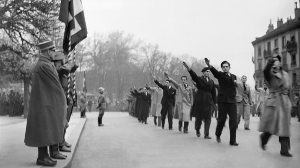 Eine Gruppe Schweizer Frontisten marschiert 1938 während der Dufourfeier in Genf an einem Offizier vorbei.