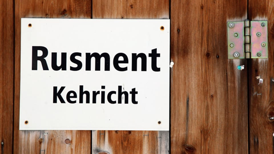 Ein Hinweisschild in den beiden Sprachen Romanisch und Deutsch hängt an einer Kehrichtsammelstelle in Stierva hoch über dem bündnerischen Albulatal.