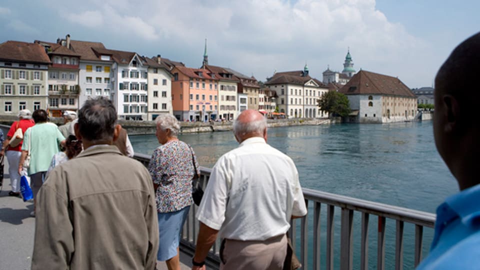 Fussgänger überqueren auf der Wengibrücke in Solothurn die Aare. Rechts im Hintergrund ist das Landhaus zu sehen.