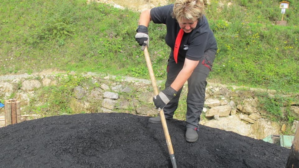 Köhlerin Doris Wicki ist die Chefin auf dem Kohleplatz. Sie schaufelt gerade das Loch für die glühende Kohle frei.