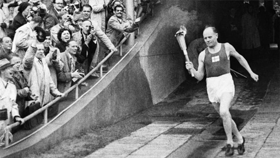 Olympische Sommerspiele 1952 Helsinki: Unter frenetischem Jubel des Publikums trägt der frühere finnische Spitzenläufer Paavo Nurmi die Fackel mit dem Olympischen Feuer ins Stadion.