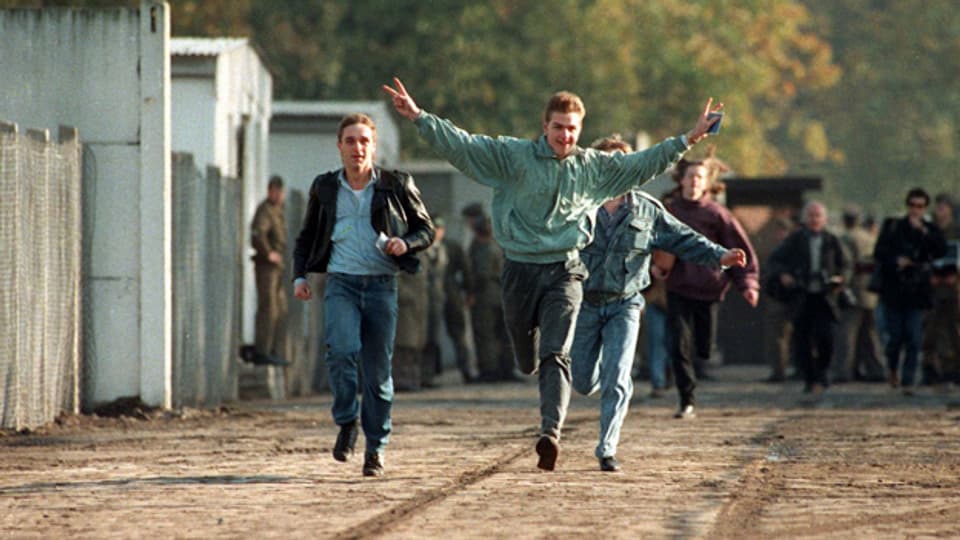 Jubelnd laufen drei junge Ost-Berliner am 10. November 1989 durch einen Berliner Grenzübergang.