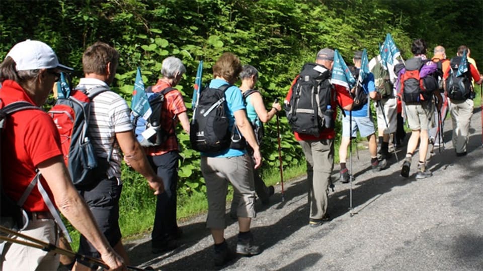 Mit der Fahne der Schweizerischen Chorvereinigung im Gepäck legt die Wandergruppe Kilometer um Kilometer zurück.
