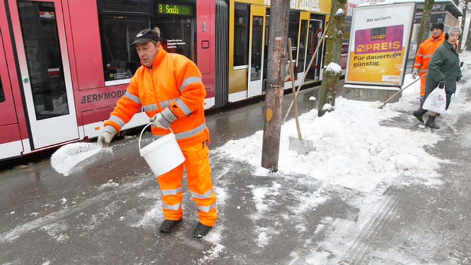 Ein Mitarbeiter der Stadt Bern streut Salz bei einer Tramhaltestelle